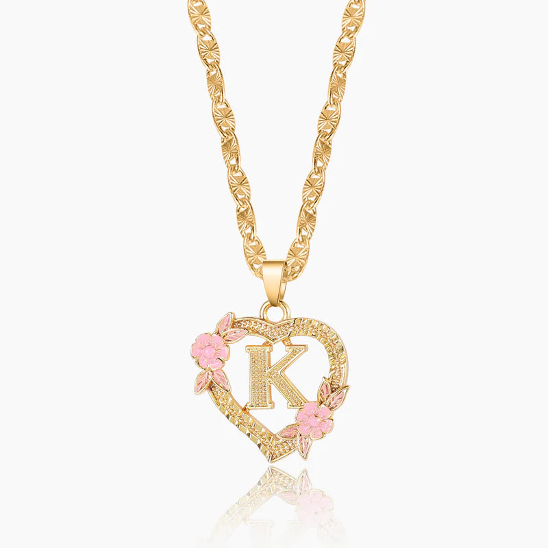 Gold necklace with a heart-shaped pendant featuring the letter 'K' and pink flowers on a white background